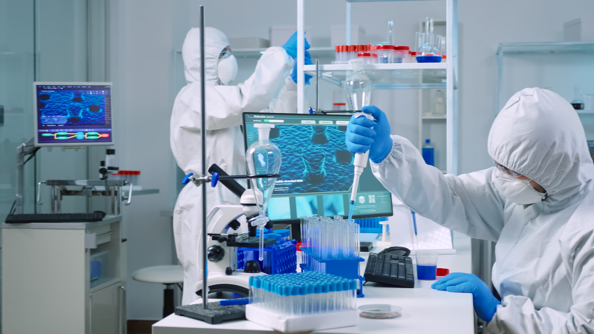 Scientist wearing coverall in equipped medical laboratory examining drug discovery with micropipette. Biochemists analysing virus evolution using high tech researching vaccine against covid19